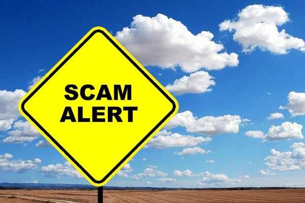 A yellow diamond-shaped road sign with the words "SCAM ALERT" in black letters, set against a blue sky and a barren landscape—a timely warning for anyone seeking a paving contractor in Hunterdon, Mercer County NJ & Bucks County PA.