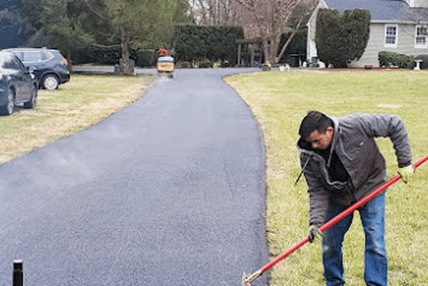 Heavy asphalt paving machine laying new driveway surface.