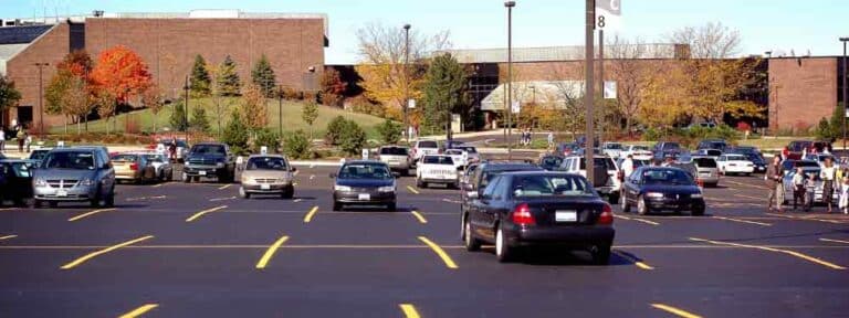 Parking lot with parked cars in front of a large brick building